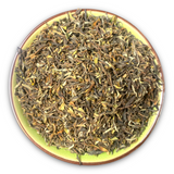 Eine Teeschale mit dem Trockenprodukt des Nepal Jun Chiyabari SFTGFOP1, bestehend aus luftigen, gedrehten Blättern in Grüntönen mit goldenen Tips