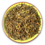 Eine Teeschale mit dem Trockenprodukt des Nepal SF SFTGFOP1 Jun Chiyabari, bestehend aus kunstvoll gedrehten Blättern in verschiedenen Brauntönen.