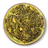 Eine Teeschale mit dem Trockenprodukt des Mellow Mandarine Bio, bestehend aus grünem Tee, Mandarinenstücken, Orangenschalen und Ringelblumen.