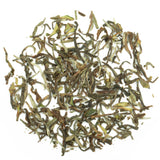 Eine Teeschale mit dem Trockenprodukt des Nepal Jun Chiyabari – Himalayan Bouquet Oolong, bestehend aus bräunlich, silbrig schimmernden, gekräuselten Blättern