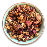 Teeschale gefüllt mit dem Früchtetee 'Alma's Liebe'. Zu sehen sind Apfelstückchen, Erdbeeren, Hibiskusblüten und Hagebuttenschalen