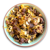 Eine Teeschale mit dem Trockenprodukt des Früchtetees 'Von der Sonne geküsst Bio', bestehend aus Weinbeeren, Mangostücken, Orangenschalen und Ringelblumen