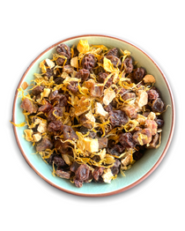 Eine Teeschale mit dem Trockenprodukt des Früchtetees 'Von der Sonne geküsst Bio', bestehend aus Weinbeeren, Mangostücken, Orangenschalen und Ringelblumen